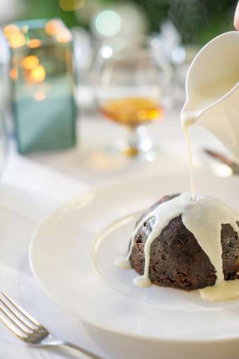 christmas pudding with cream being poured