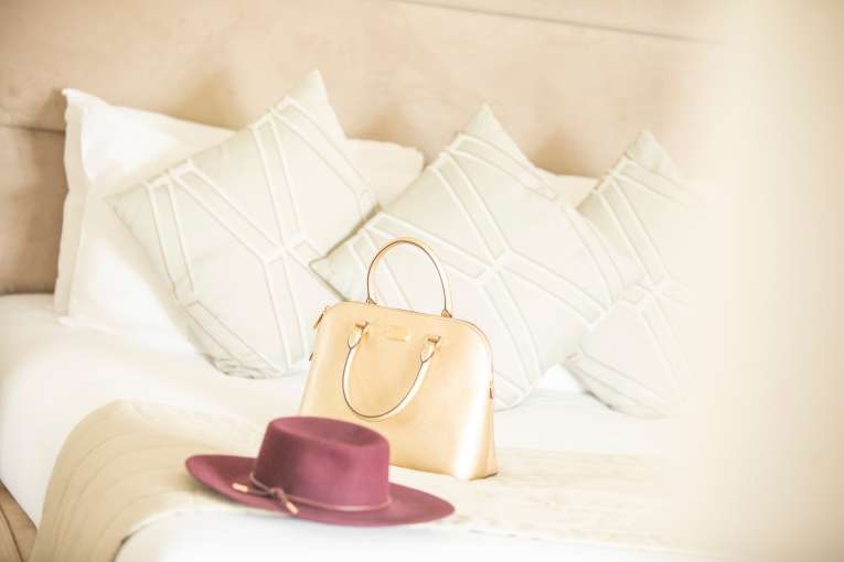 Ladies hat and handbag on large hotel bed