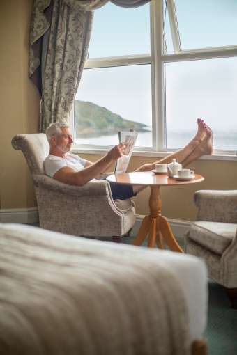 Male guest with his feet up enjoying a stunning sea view from his hotel room