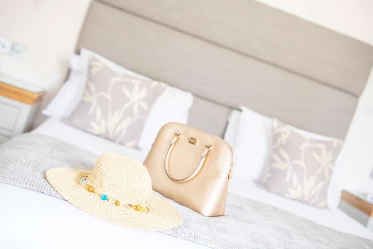 Summer hat and handbag on large hotel bed