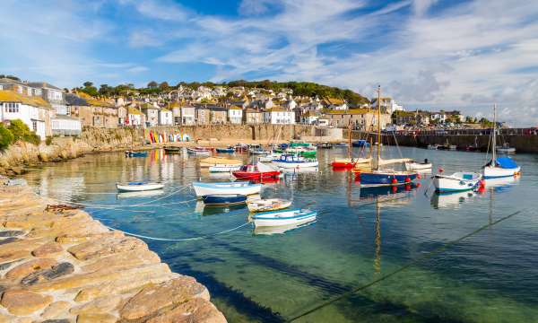 Boats moored in crystal clear waters at Mousehole in Cornwall