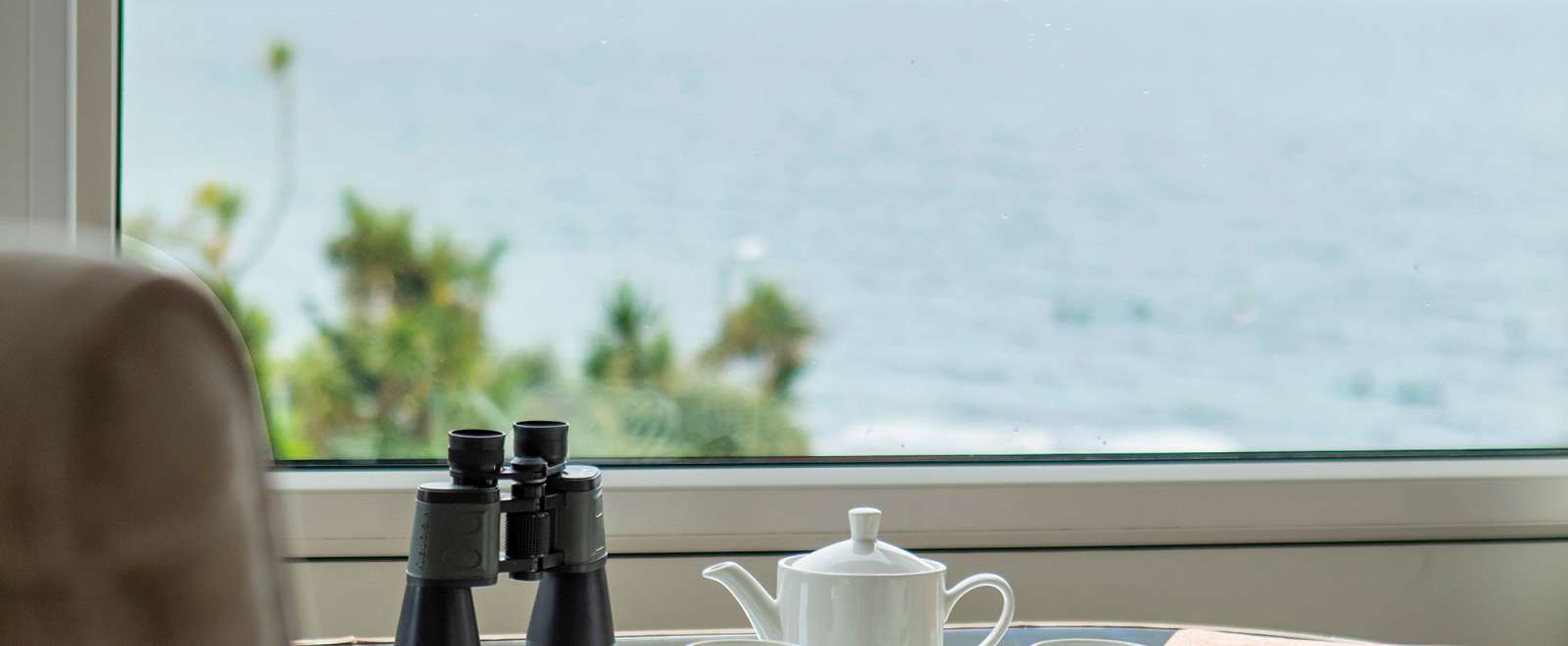 Binoculars and teapot set in front of hotel room with stunning sea view of Falmouth bay