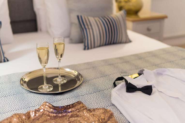 Royal Duchy Hotel Christmas Party Outfits on Bed with Flutes of Champagne