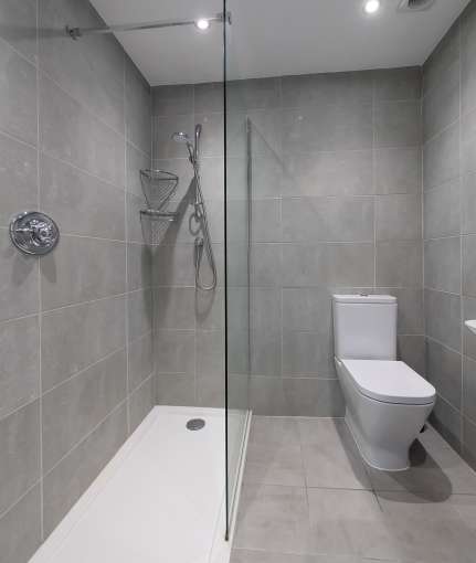 walk in shower with grey tiles