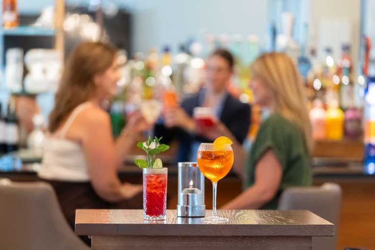 Ladies at the bar talking with focus on drinks on the table infront 