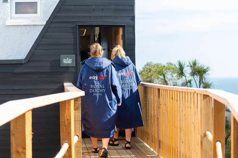 Ladies in DryRobes walking to the entrance of The Duchy Beach House