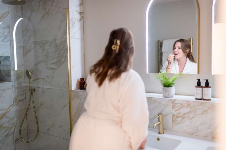 Lady putting on make up in the bathroom at The Duchy Beach House