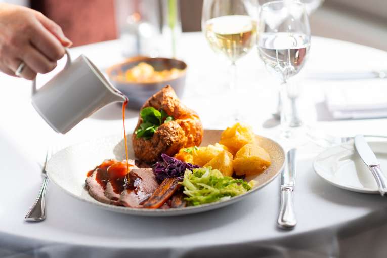 Someone pouring gravy on roast beef at The Royal Duchy Hotel