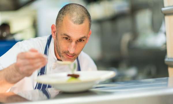 Royal duchy hotel chef John in kitchen serving food.