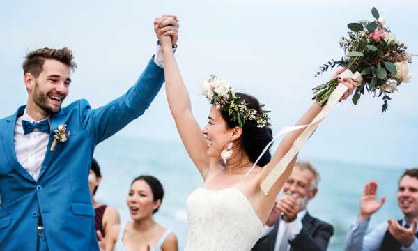 Newly married couple embracing in evening at their wedding with sea in background