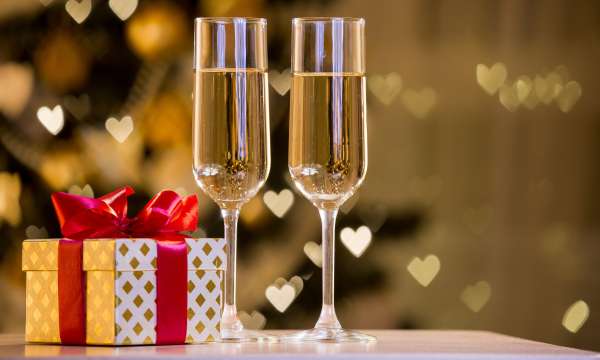 Two glasses of champagne in front of a gift wrapped in gold paper 