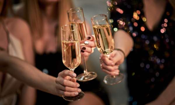 Three people holding filled champagne glasses and cheersing together