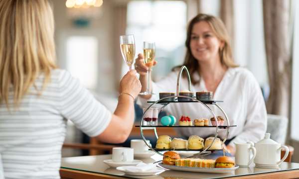 Two Ladies enjoying afternoon tea and cheersing their glasses of Champagne