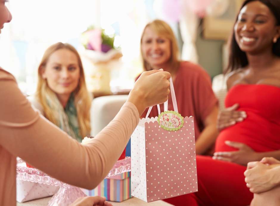 Baby shower pregnant woman and friends sharing gifts