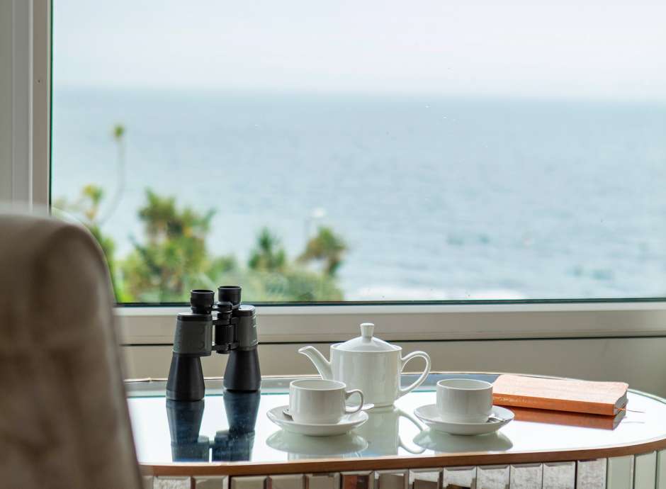 Binoculars and teapot set in front of hotel room with stunning sea view of Falmouth bay