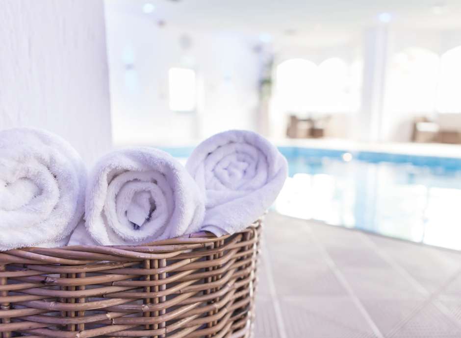 Fresh spa towels in basket next to indoor pool