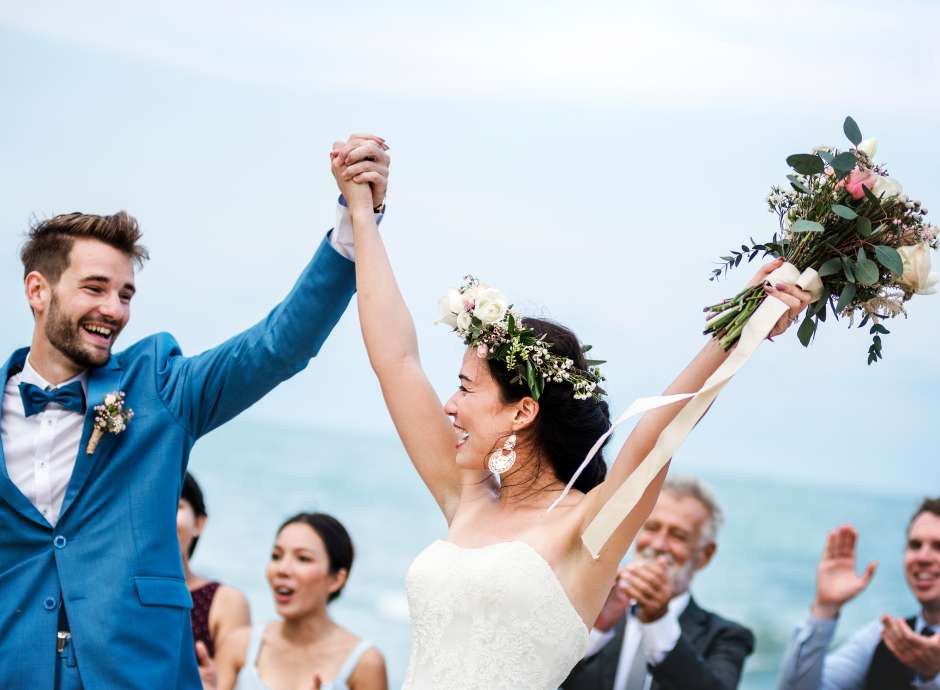 Newly married couple embracing in evening at their wedding with sea in background