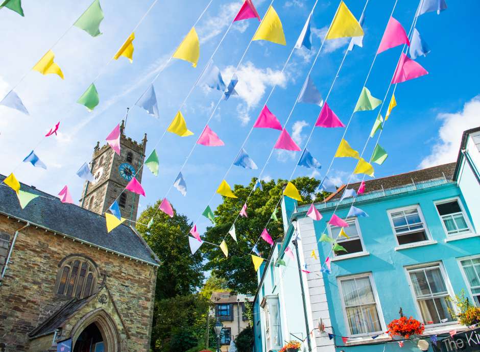 Colourful bunting flying between shops on summers day in Falmouth High Street