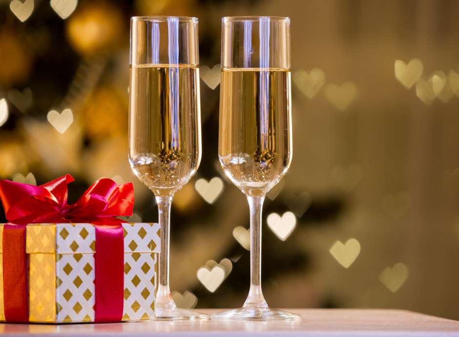 Two glasses of champagne in front of a gift wrapped in gold paper 