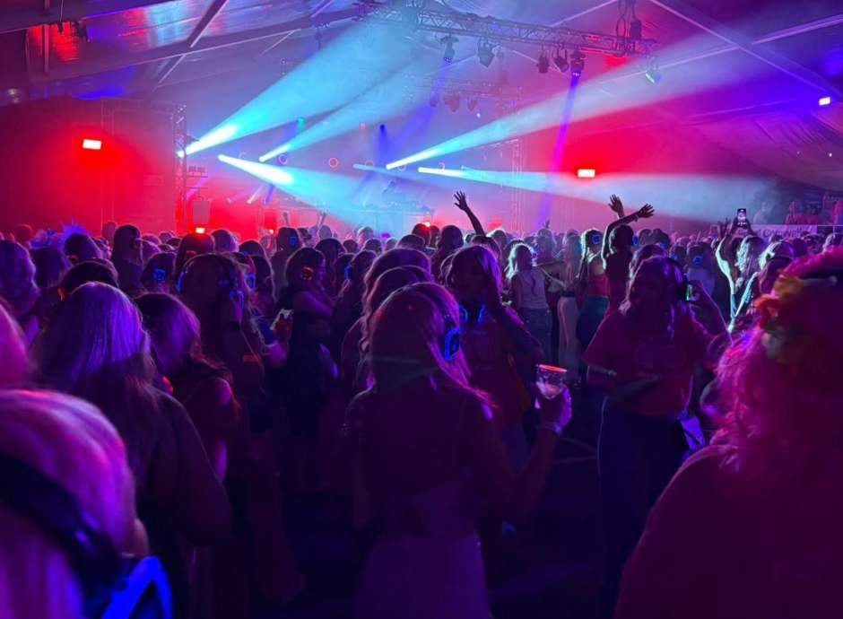 People dancing in a tent with lights at the Falmouth Pink Wig March