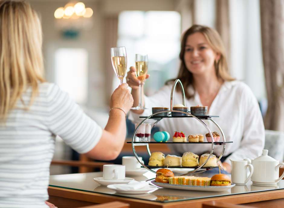Two Ladies enjoying afternoon tea and cheersing their glasses of Champagne 