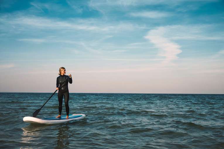 Female Stand up paddleboarding at sea