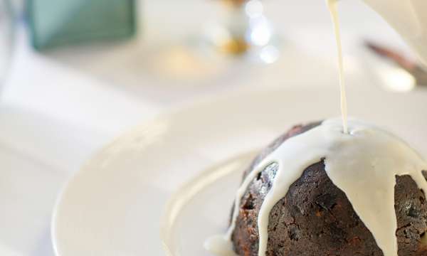 christmas pudding with cream being poured