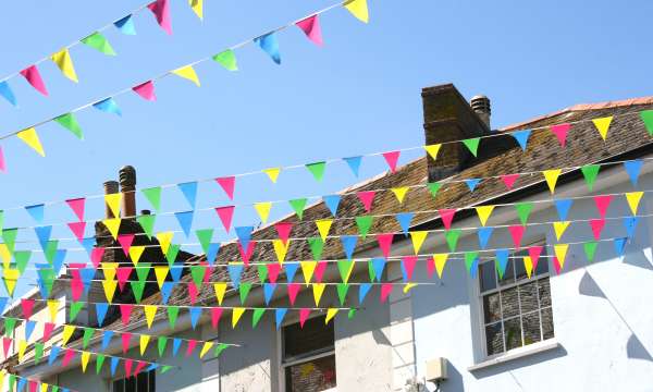 Colourful bunting flying between shops on summers day in Falmouth High Street