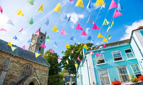 Colourful bunting flying between shops on summers day in Falmouth High Street