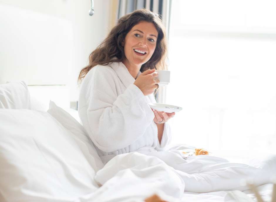 Female hotel guest enjoying breakfast in bed 
