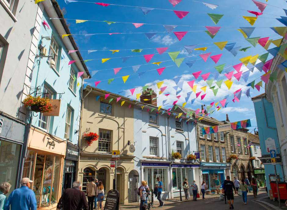 Colourful bunting flying between shops on summers day in Falmouth High Street